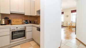 A modern kitchen with white cabinets, a built-in oven, and a wooden countertop.