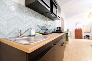 A modern kitchen with a herringbone tile backsplash, stainless steel sink, and wooden cabinetry.