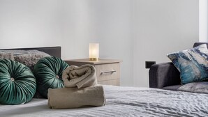 A neatly made bed with a folded towel, two green pillows, a bedside lamp, and a nightstand with a drawer. - Rainfall Shower | Pool/Snooker | x 4 Cars (Berkshire)