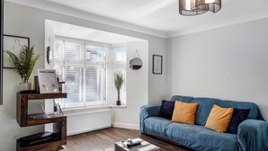 A modern living room with a blue sofa, wooden coffee table, and a radiator. - Rainfall Shower | Pool/Snooker | x 4 Cars (Berkshire)