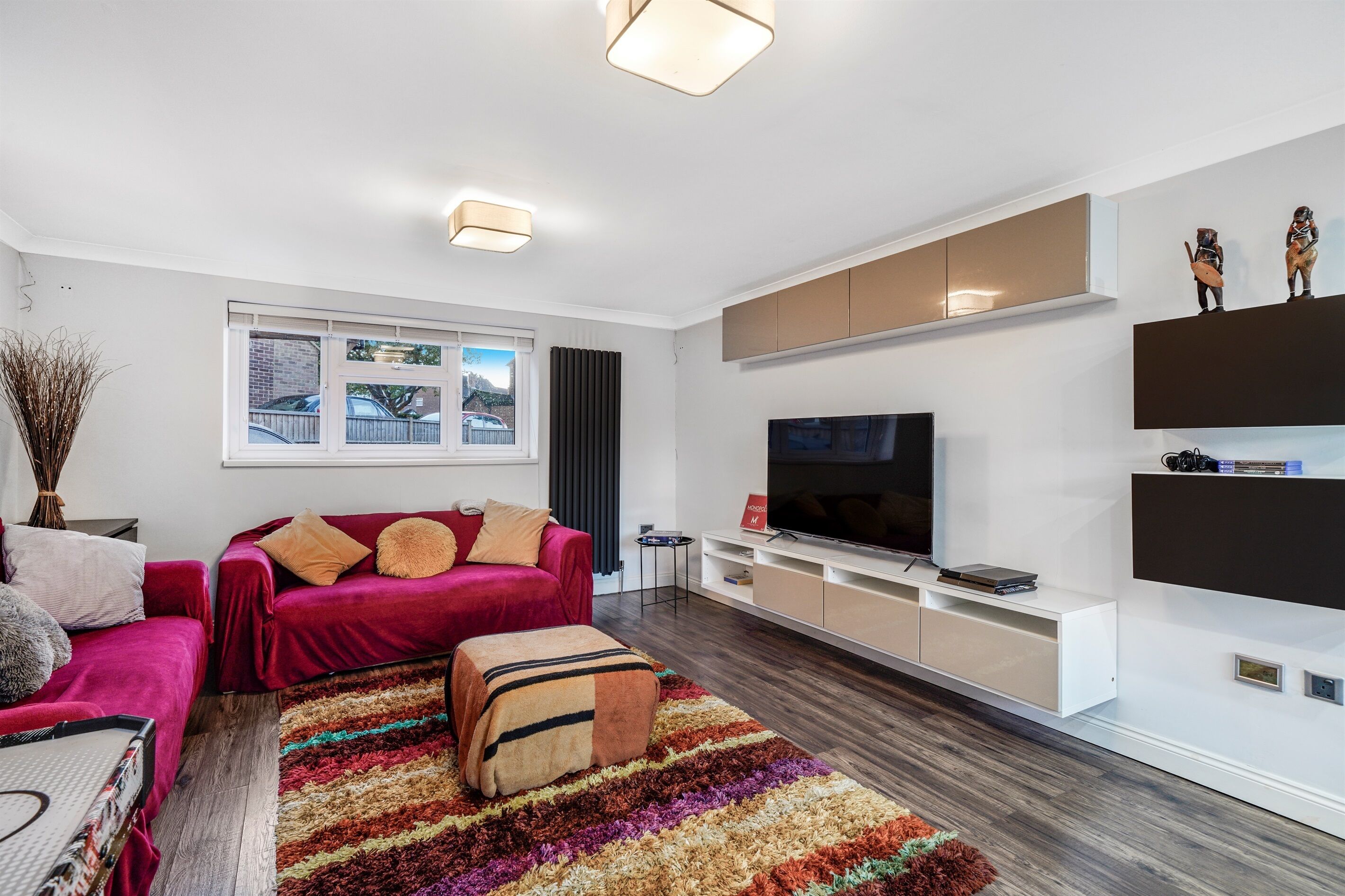 A modern living room with a red sofa, a TV, and a white entertainment unit.