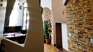 Un interior moderno con una pared de acento de piedra, una zona de comedor con separador de vidrio y una lámpara colgante.