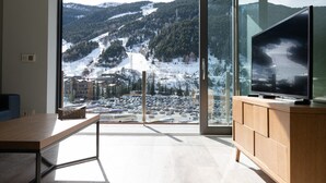 Una habitación moderna con un ventanal grande que ofrece vistas a una montaña nevada y un estacionamiento.