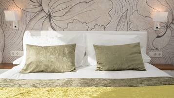 A bed with two pillows, a patterned wall, and two wall-mounted lamps.