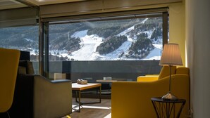 Habitación moderna con un ventanal amplio que ofrece vistas a un paisaje montañoso nevado.