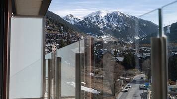 A mountain view from a balcony with a road and buildings in the foreground.
