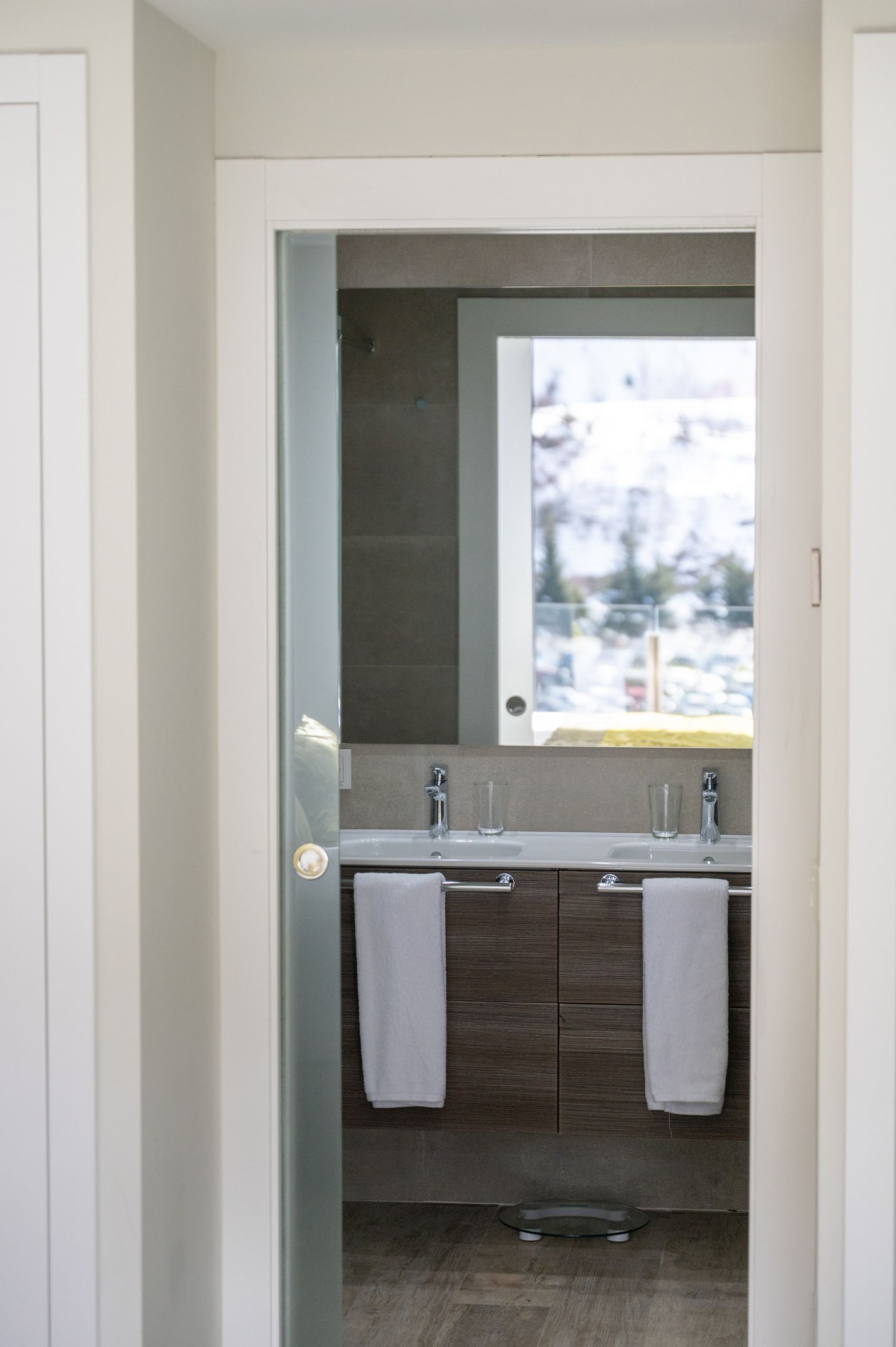 A modern bathroom with a large mirror, two sinks, and a towel rack.