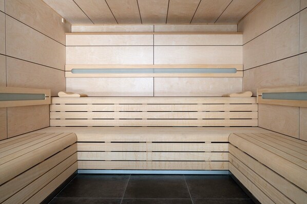 Uma sauna com bancos de madeira e teto ripado.
