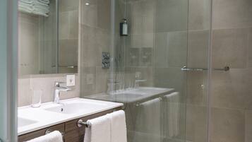 A modern bathroom with a glass shower enclosure, a white sink, and a mirror.