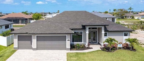 A single-story house with a grey roof, a front garage, and a well-maintained lawn.