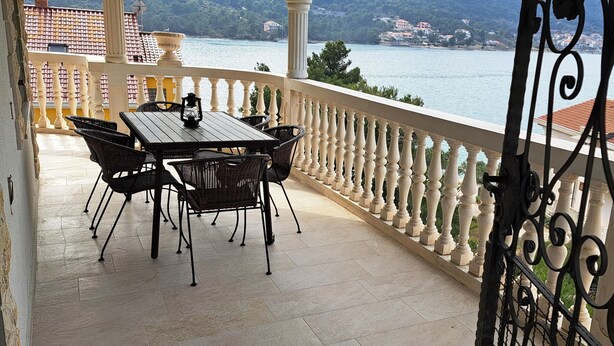 A balcony with a table and chairs, a view of a body of water, and a railing.