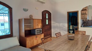 A dining area with a wooden table, chairs, a microwave, and a cabinet with a decorative item on top.