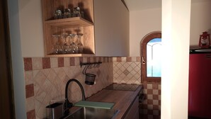 A kitchen with a granite countertop, a stainless steel sink, a hanging rack with glasses, and a window with a view.