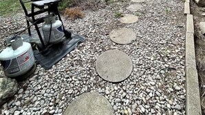 Un patio trasero con una parrilla, una mesa de barbacoa y un camino de piedra.