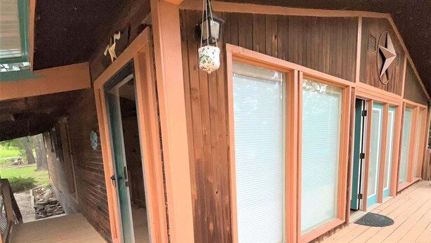 Un edificio de madera con ventanas amplias, un porche y una puerta.
