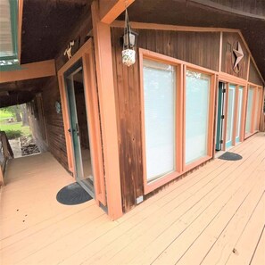 A wooden building with large windows, a porch, and a door. - The Monarch Cabin Sum (Ruidoso)