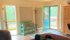 Amplia sala de estar con un sofá grande, una butaca y un mueble de madera. Hay un ventanal corredero que da a una terraza exterior.