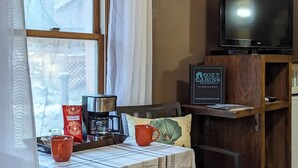 A cozy cabin with a television, a coffee maker, and a sign for Cozy Cabins Real Estate. - Cottages at Canyon Creek #1 (Ruidoso)