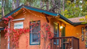 A rustic cabin labeled "COTTAGE" with a porch, two chairs, and a small table.