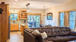 Un salon chaleureux avec un canapé en cuir marron, des meubles en bois et un coin repas comprenant une table et des chaises.