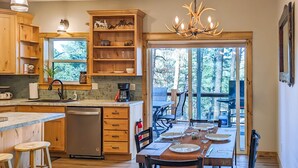 Une cuisine dotée de meubles en bois, d’un lave-vaisselle et d’un coin repas avec une table dressée pour quatre personnes.
