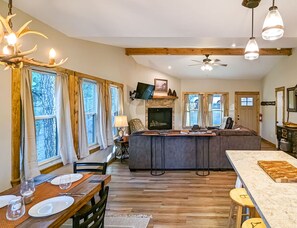 A spacious kitchen with a central island, wooden beams, and a fireplace.