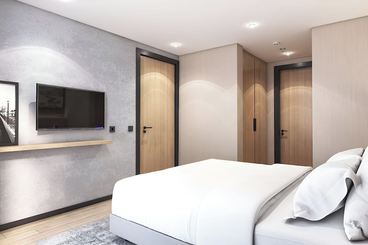 Een moderne slaapkamer met een bed, een wandtelevisie en inbouwmeubels.