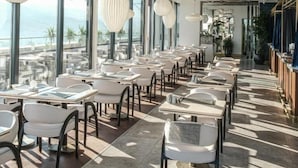 Un restaurant moderne doté d’une grande salle à manger, de larges fenêtres et de luminaires suspendus.