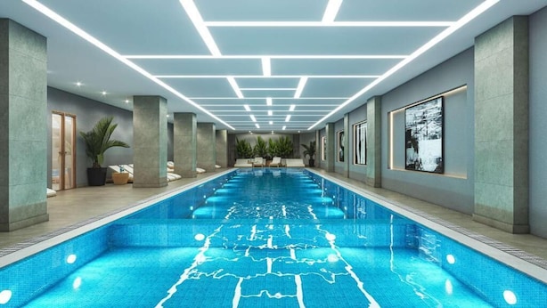Une longue piscine intérieure au design moderne, entourée de murs ornés de tableaux encadrés et de plantes en pot.