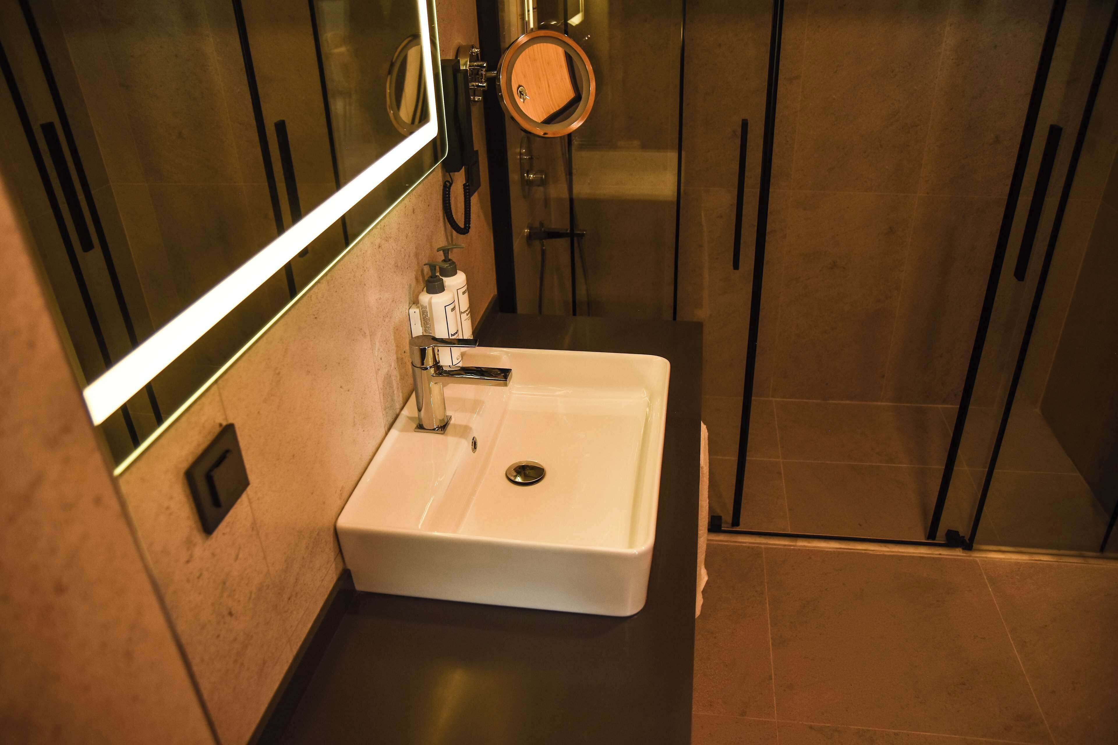 Une salle de bain avec un lavabo blanc, un miroir et un espace douche.