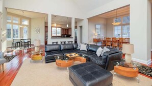 A spacious living room with a sectional sofa, coffee tables, and a dining area with chairs. - Portside Villa Luxury Rental on Lake Gaston (Bracey)