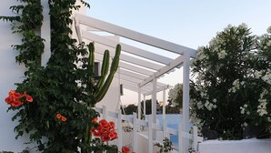 A white pergola structure with climbing plants and flowers. - Sagma Central (Santorini)