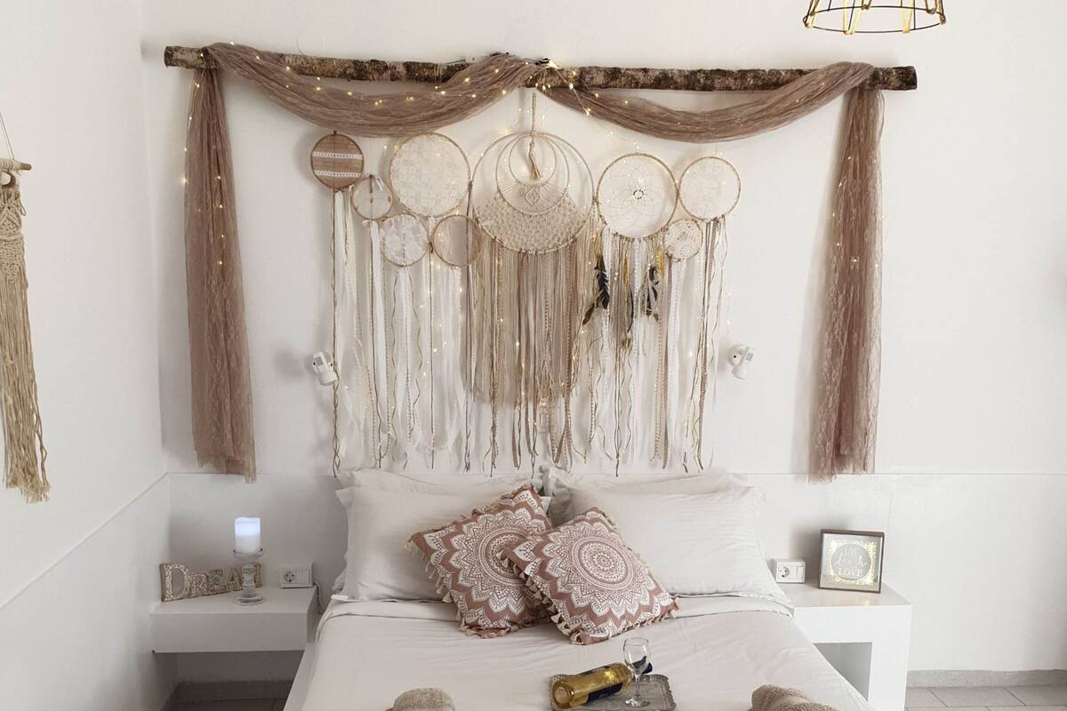 A bedroom with a bed, pillows, a bedside table, and a wall decoration.