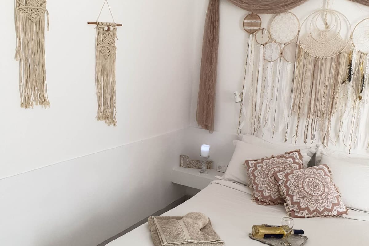 A bedroom with a bed, pillows, a bedside table, and wall decorations.