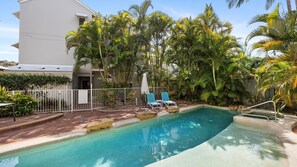 Relax by the serene pool surrounded by lush tropical vegetation and palm trees.