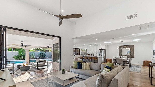 A modern living room with a sofa, coffee table, and a dining area with chairs. - Casa De Sol - McCormick Ranch * 5BR w/ Heated Pool (Scottsdale)