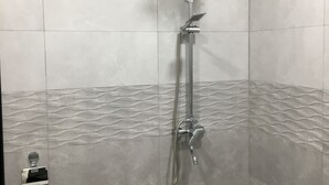 A bathroom with a shower, tiled walls, and a toilet. - Hotel KA-EL (Parakar)
