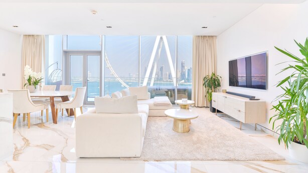 Ein modernes Wohnzimmer mit großem Fenster, einer Couch, einem Esstisch und einem Fernseher.
