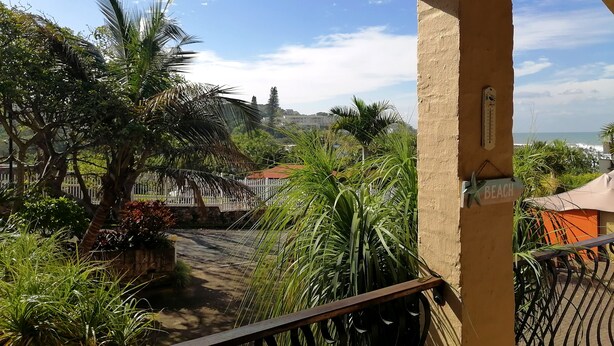 A balcony with a view of a beach, palm trees, and a white fence. - Crayfish Inn No.4 (Margate)