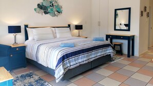 A bedroom with a bed, bedside tables, a dresser, a mirror, and a wall decoration.