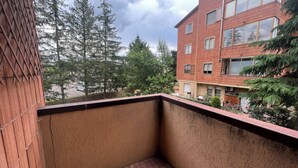 A balcony with a view of a multi-story building, trees, and a parked bicycle. - Apartment in the exhibition center, clinic, near the historic center (Arezzo)