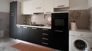 A modern kitchen with black and white cabinets, a built-in oven, a microwave, and a washing machine. - Apartment in the exhibition center, clinic, near the historic center (Arezzo)