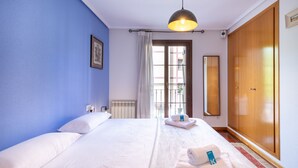 A hotel room with a large bed, a wardrobe, a window with curtains, and a hanging light fixture. - Eihera - baskeyrentals (Irun)