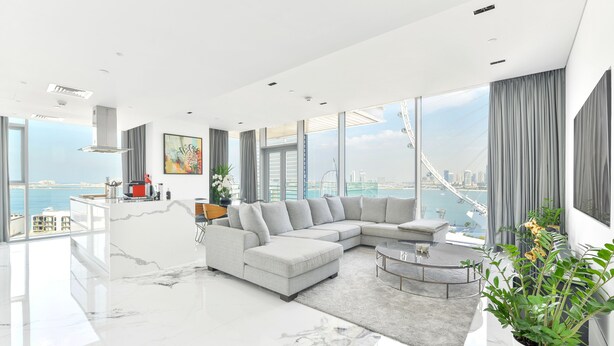 Ein modernes Wohnzimmer mit einer großen Eckcouch, einem Couchtisch und Blick auf die Stadt und das Wasser.