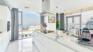 Eine moderne Küche mit einer großen Kochinsel, Edelstahlgeräten und Blick auf die Stadtlandschaft.