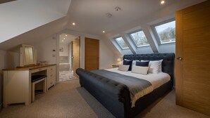 Ein Schlafzimmer mit einer Schlafgalerie, einem Bett mit dunklem Kopfteil, einem Holztisch und einem Kleiderschrank.