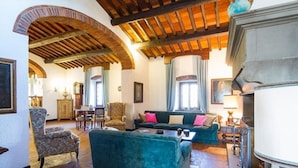 A spacious living room with a high wooden ceiling, a fireplace, and comfortable seating.