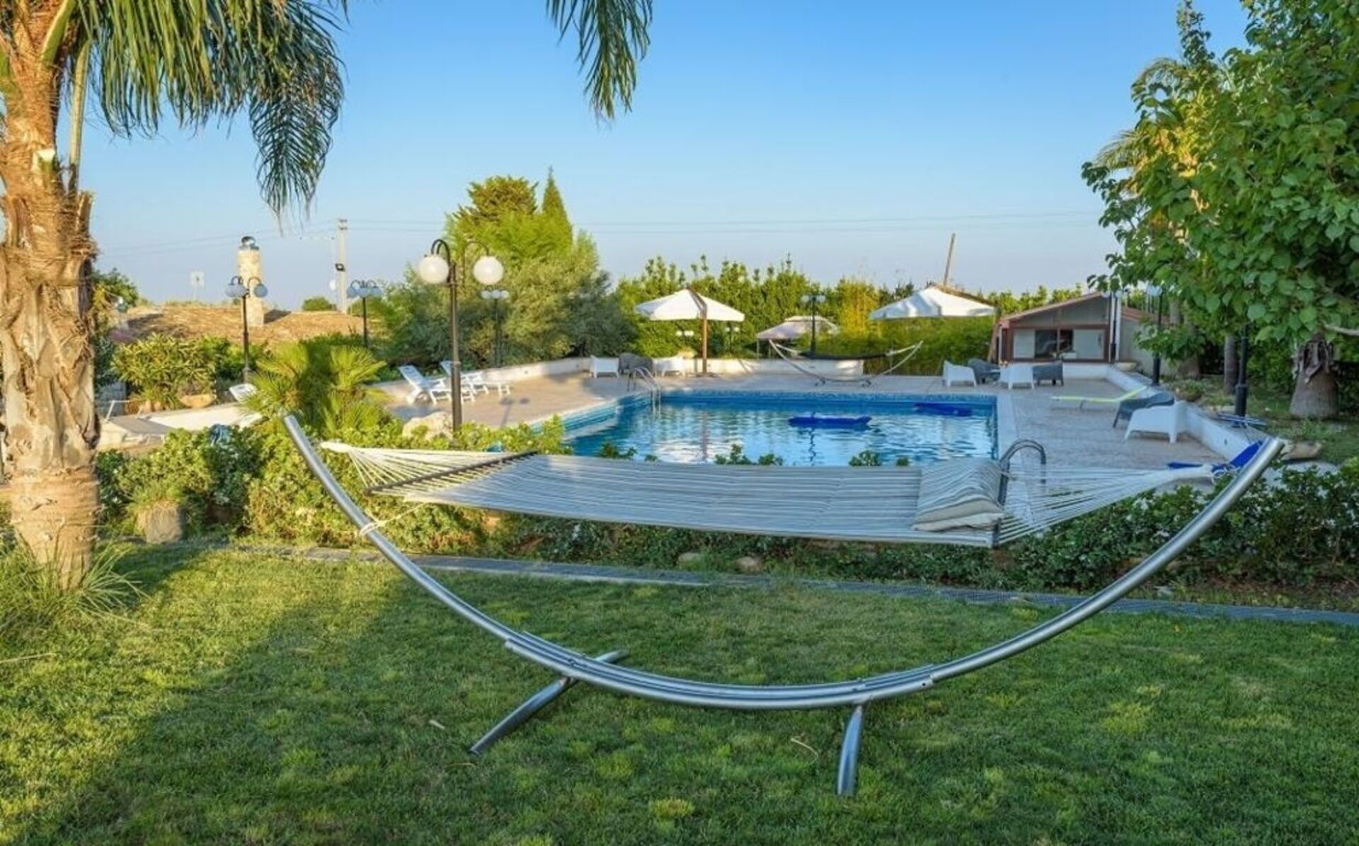 Un giardino con piscina, un'amaca e mobili da esterno.