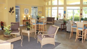 A spacious living area with wicker furniture, a glass coffee table, and a view through large windows. - Smart home near Disney World, Universal Studios, Silver Spurs Arena (Kissimmee)
