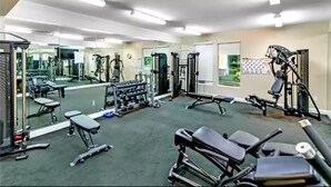 A gym with various exercise equipment, mirrors, and a carpeted floor. - Smart home near Disney World, Universal Studios, Silver Spurs Arena (Kissimmee)